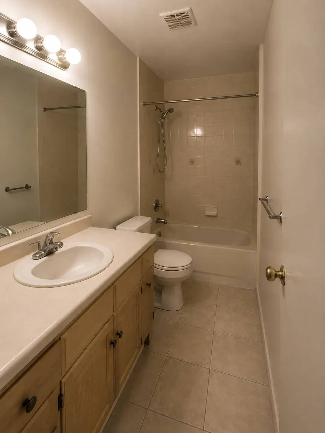 Before: a dated bathroom with an oak vanity, cultured marble top, and an alcove tub