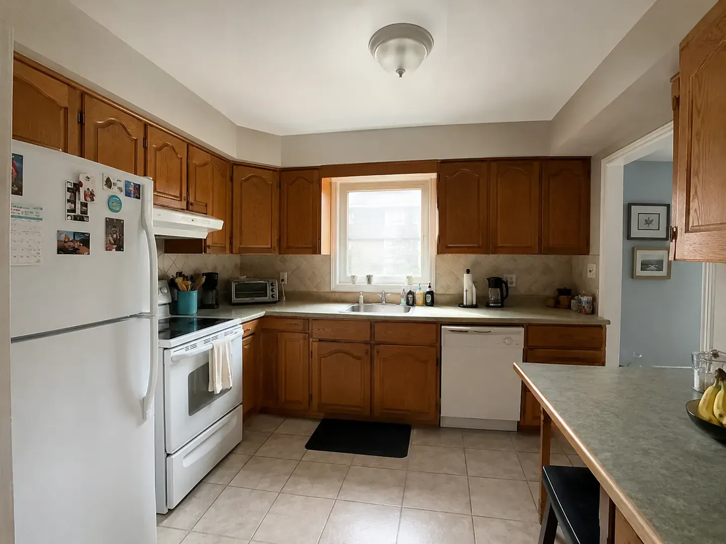 Before: a dated Toronto kitchen with oak cabinets, white appliances, and a beige tile floor