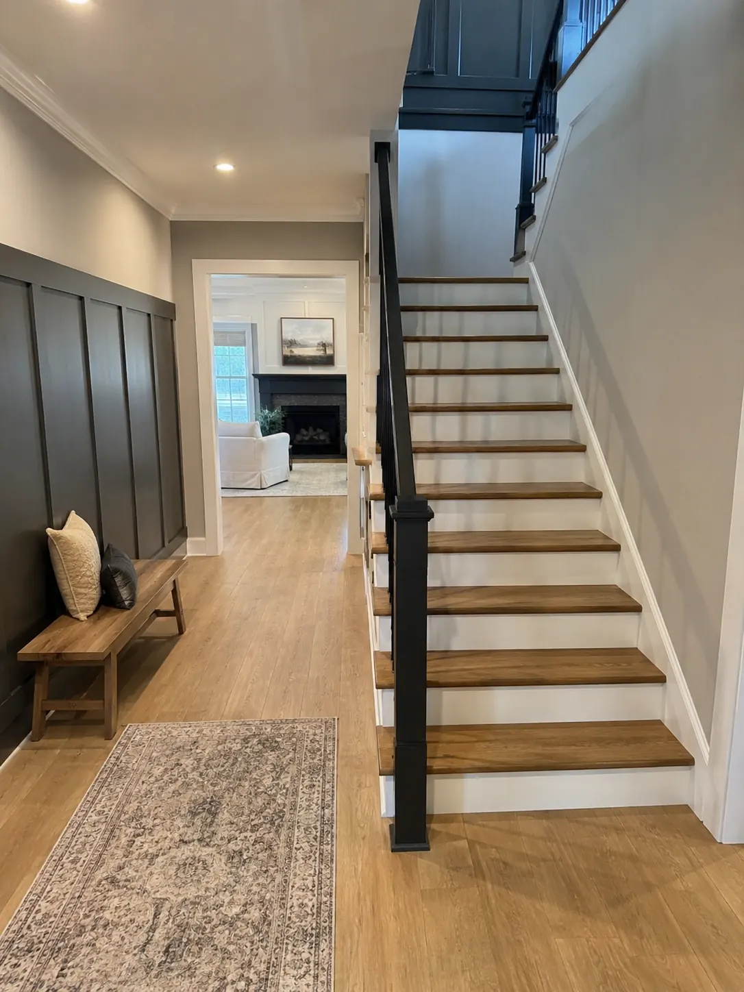 Renovated Toronto stair hall with board and batten panelling, oak treads, and a black railing