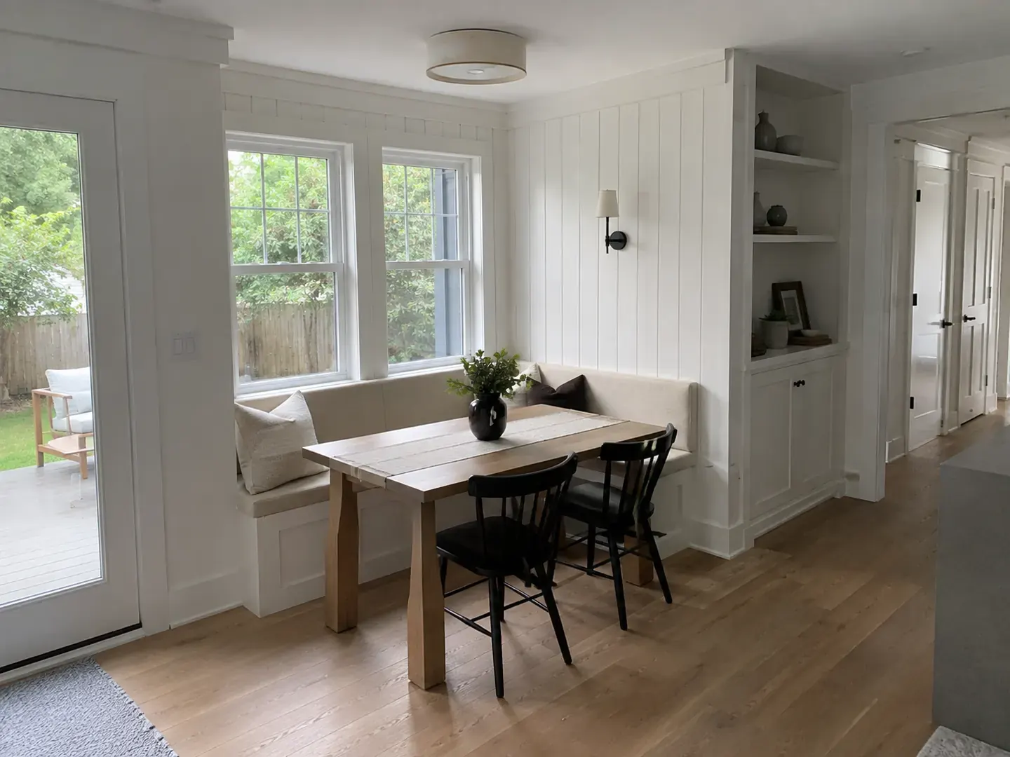 Renovated Toronto dining nook with a built-in banquette, panelled walls, and windows onto the garden