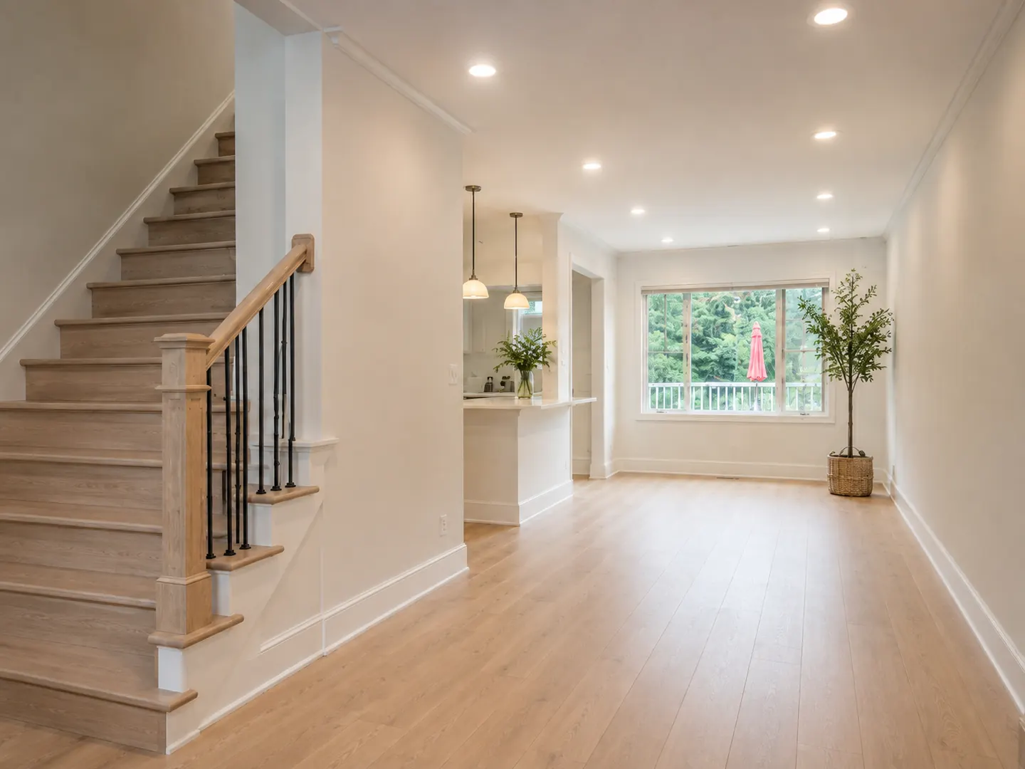 After: the same main floor opened up with a white oak stair, black iron spindles, wide plank floors, flat ceilings, and pot lights