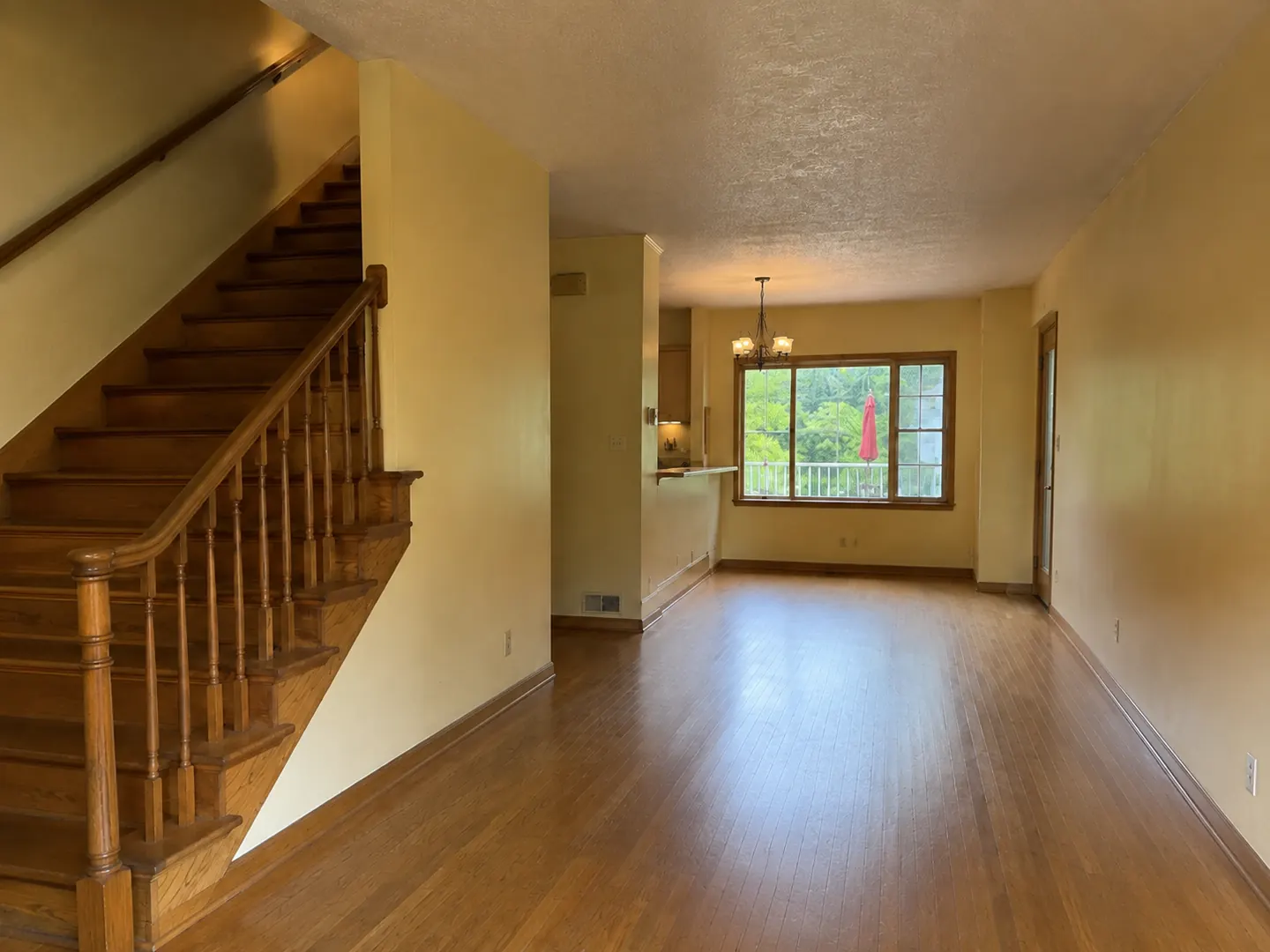 Before: a dated Toronto main floor with a closed-in stair, orange oak railings, yellowed walls, and a stippled ceiling